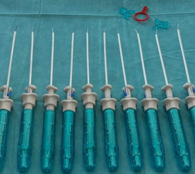 Row of endodontic files with turquoise handles laid out on a sterile blue dental drape; a small red tool sits at the top.