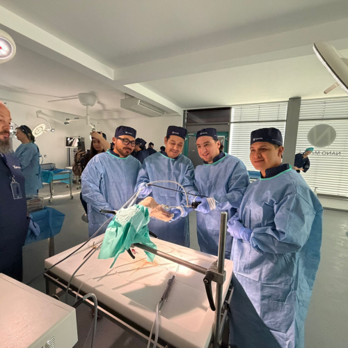 A team of surgeons in blue gowns and caps work around a patient on an operating table in a bright, sterile operating room.