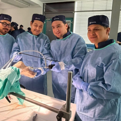 Surgical team in blue scrubs and caps perform surgery around an operating table, hands in sterile gloves.